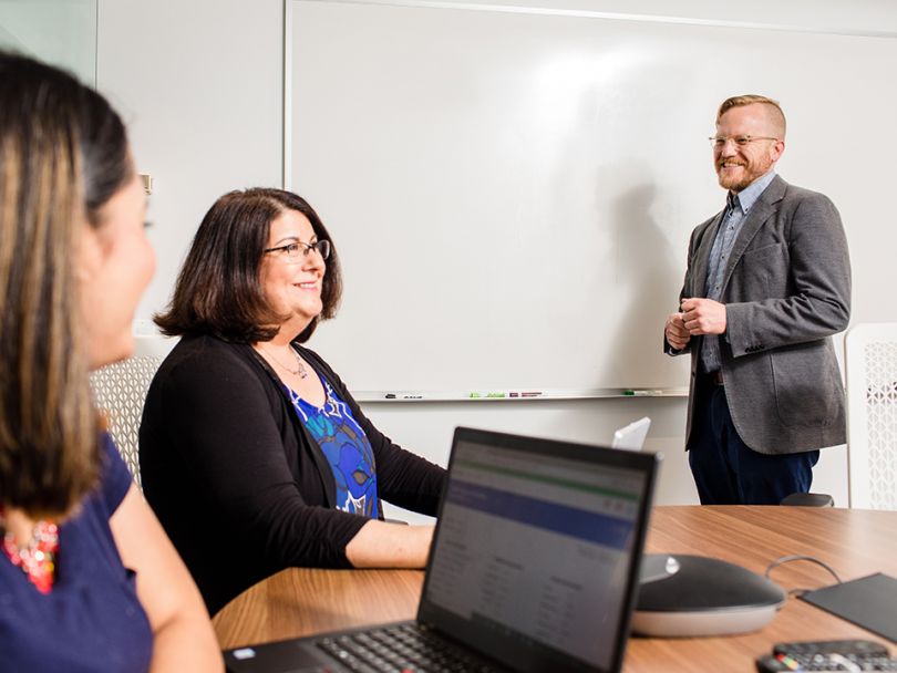 Sam Bakkan smiles while standing at a whiteboard.